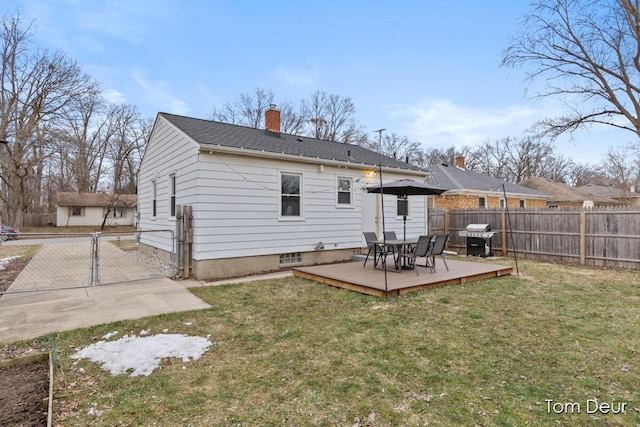 back of property with fence, a yard, a wooden deck, a gate, and a chimney