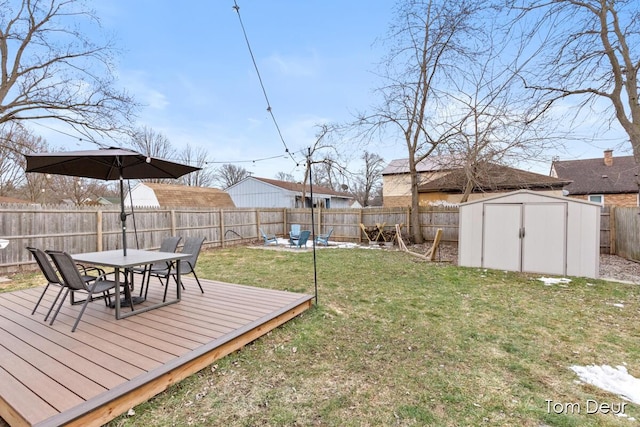 view of yard featuring a fenced backyard, an outbuilding, a wooden deck, a shed, and outdoor dining space