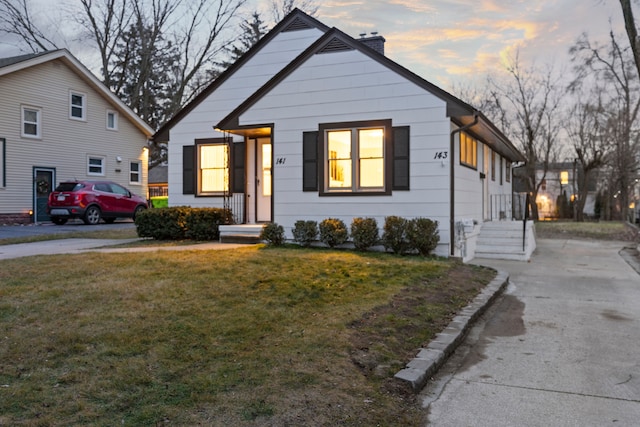 bungalow featuring a lawn and a chimney