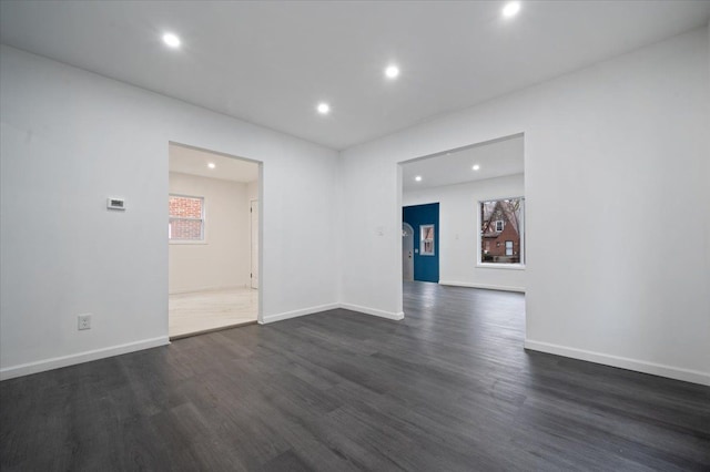 spare room featuring dark wood-style floors and baseboards