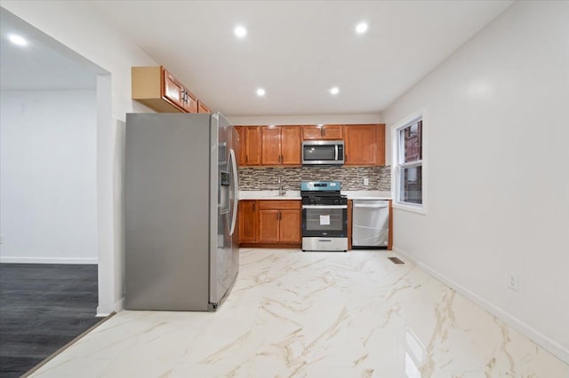 kitchen featuring marble finish floor, stainless steel appliances, baseboards, and decorative backsplash