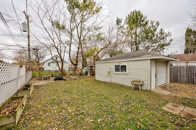 view of yard featuring a fenced backyard, a detached garage, and an outbuilding