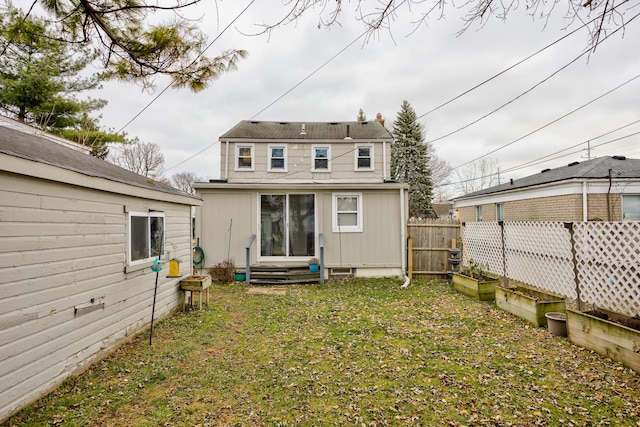 rear view of property with a yard, entry steps, and fence