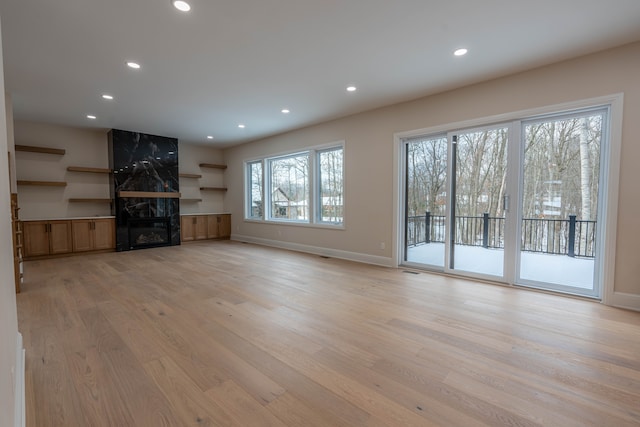 unfurnished living room featuring plenty of natural light, recessed lighting, baseboards, and light wood-style floors