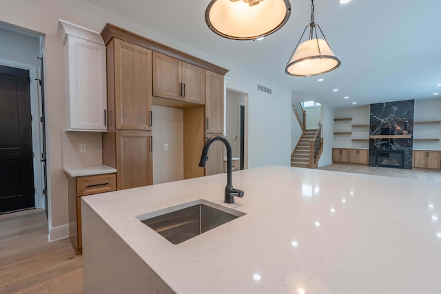 kitchen featuring a sink, visible vents, light stone countertops, and decorative light fixtures