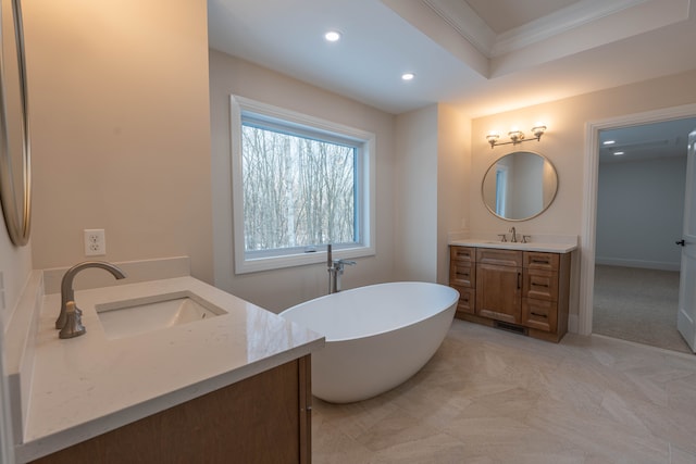 bathroom with a freestanding bath, two vanities, recessed lighting, and a sink