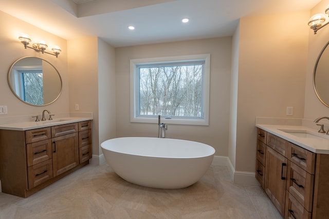 bathroom with a sink, baseboards, a soaking tub, and two vanities