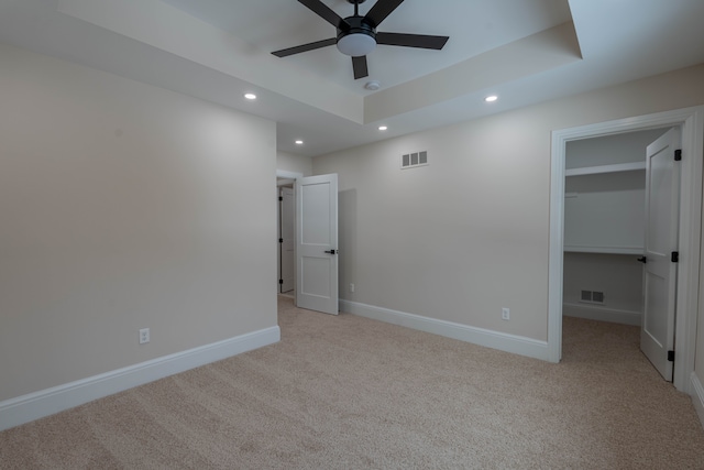 unfurnished bedroom featuring visible vents, baseboards, a tray ceiling, light carpet, and recessed lighting