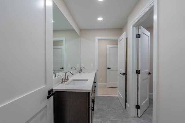 full bath featuring double vanity, baseboards, and a sink