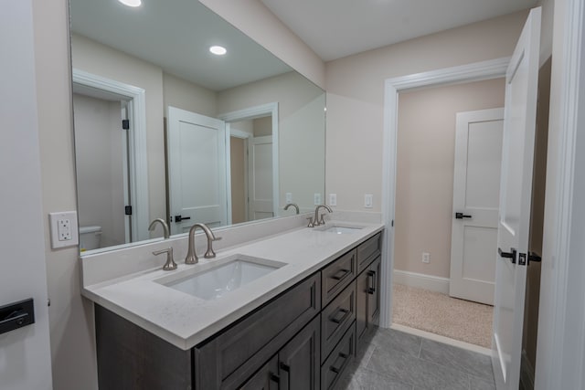 bathroom featuring a sink, baseboards, recessed lighting, and double vanity