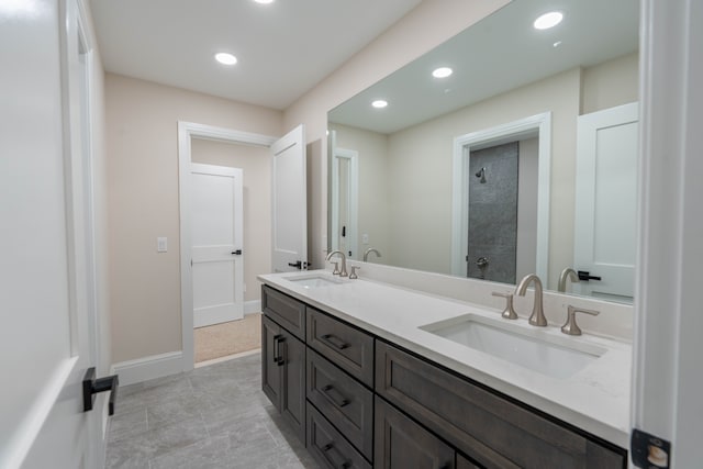 bathroom with a sink, baseboards, recessed lighting, and a tile shower