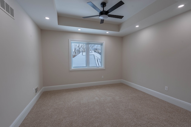 carpeted spare room featuring visible vents, baseboards, ceiling fan, recessed lighting, and a raised ceiling