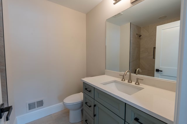 full bathroom with visible vents, baseboards, toilet, a tile shower, and vanity