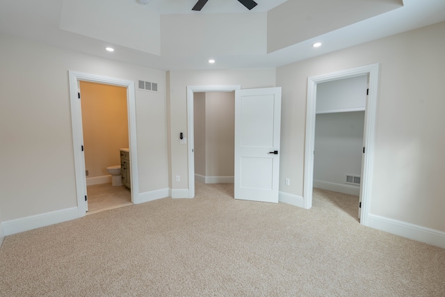 unfurnished bedroom featuring a walk in closet, recessed lighting, visible vents, and light carpet