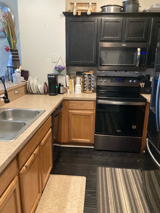 kitchen featuring light countertops, appliances with stainless steel finishes, dark wood-type flooring, and a sink