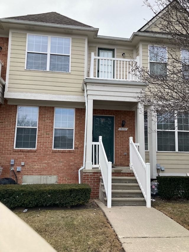 view of front of property featuring brick siding and a balcony