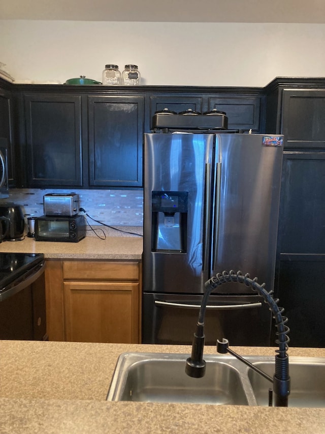 kitchen featuring a sink, light countertops, black range with electric cooktop, and stainless steel fridge