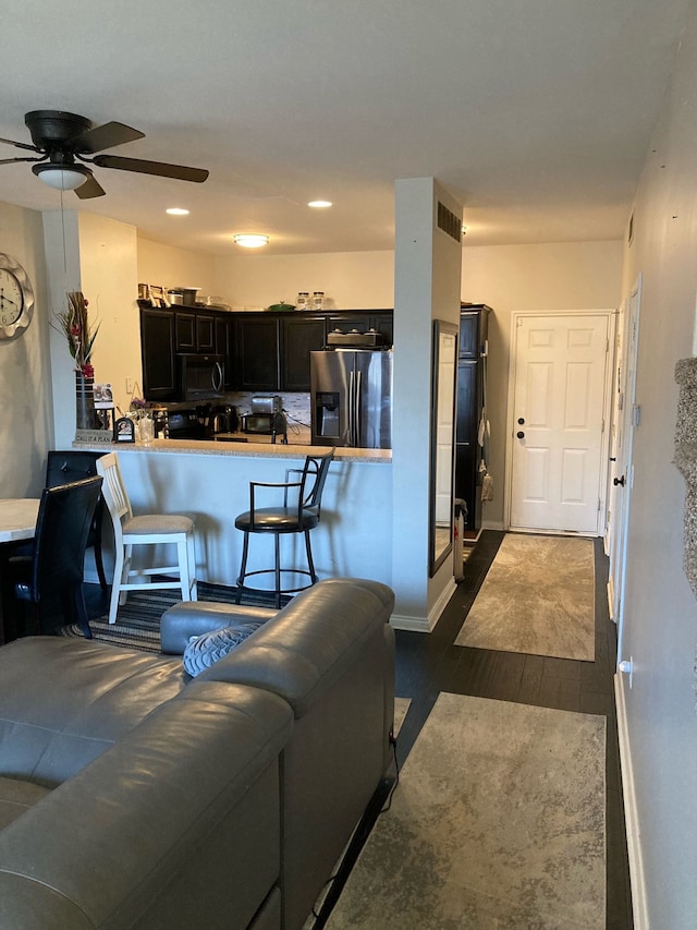 living room featuring ceiling fan, recessed lighting, dark wood-style flooring, visible vents, and baseboards