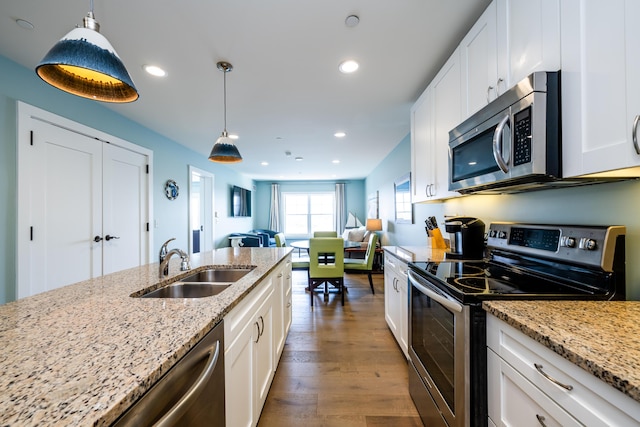 kitchen featuring white cabinets, dark wood finished floors, stainless steel appliances, a sink, and recessed lighting