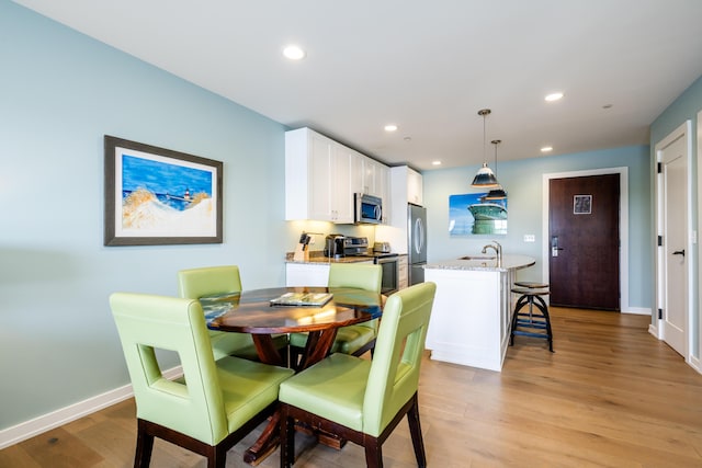 dining room featuring light wood-style flooring, baseboards, and recessed lighting