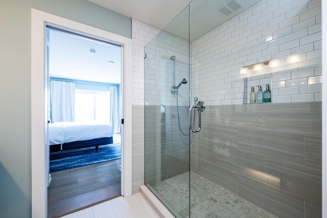 bathroom with tiled shower, connected bathroom, and visible vents