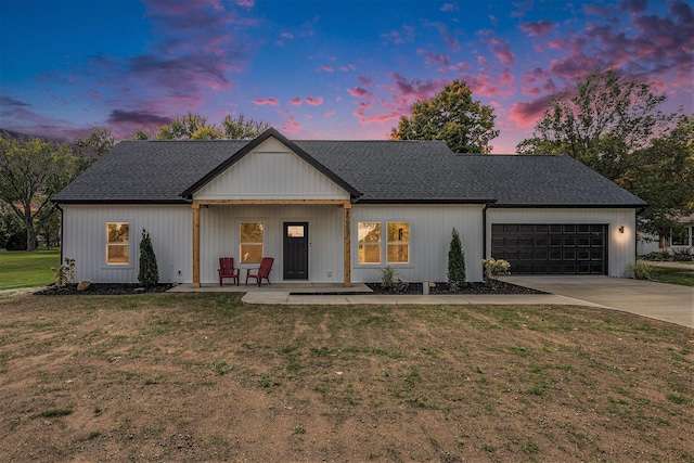 modern inspired farmhouse with driveway, a shingled roof, a lawn, and an attached garage