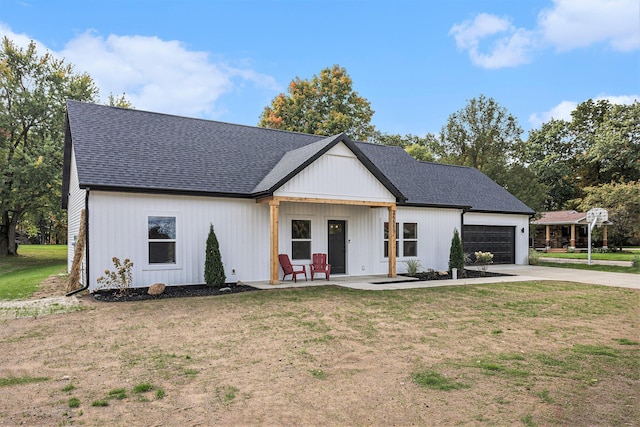 modern farmhouse with a garage, driveway, roof with shingles, and a front yard