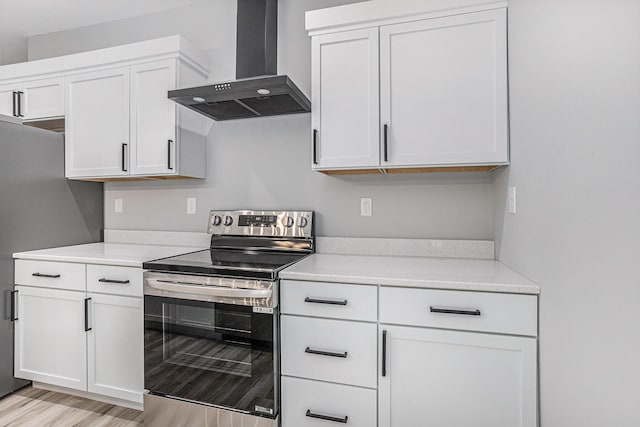 kitchen featuring white cabinets, wall chimney exhaust hood, light wood-style flooring, appliances with stainless steel finishes, and light countertops