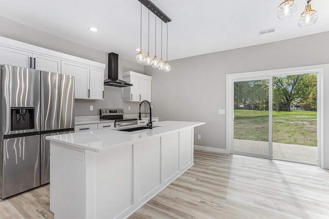 kitchen featuring a kitchen island with sink, stainless steel appliances, a sink, visible vents, and wall chimney range hood