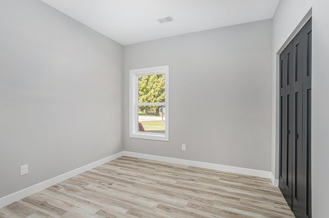 spare room featuring visible vents, light wood-style flooring, and baseboards