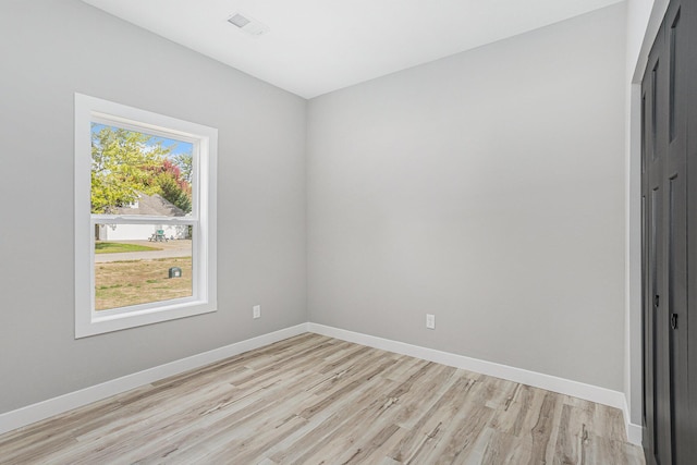 unfurnished room with light wood-type flooring, visible vents, and baseboards