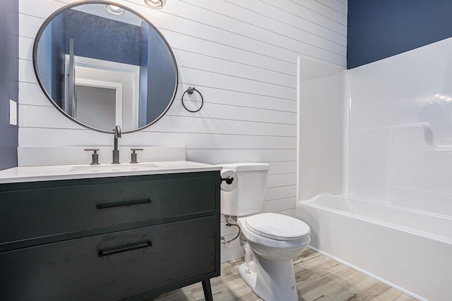 full bath featuring toilet, shower / washtub combination, wood finished floors, and vanity