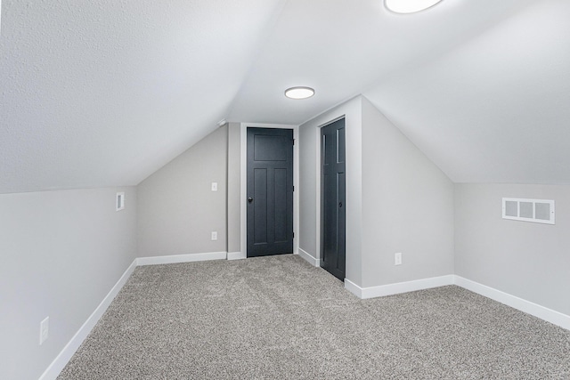 additional living space featuring carpet floors, baseboards, visible vents, and vaulted ceiling