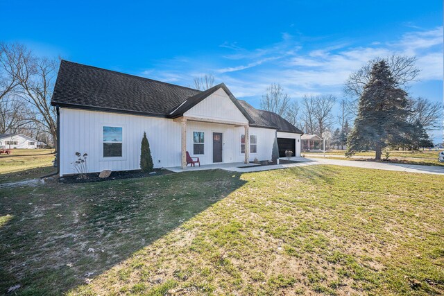 modern inspired farmhouse featuring an attached garage, a shingled roof, concrete driveway, a front lawn, and a patio area