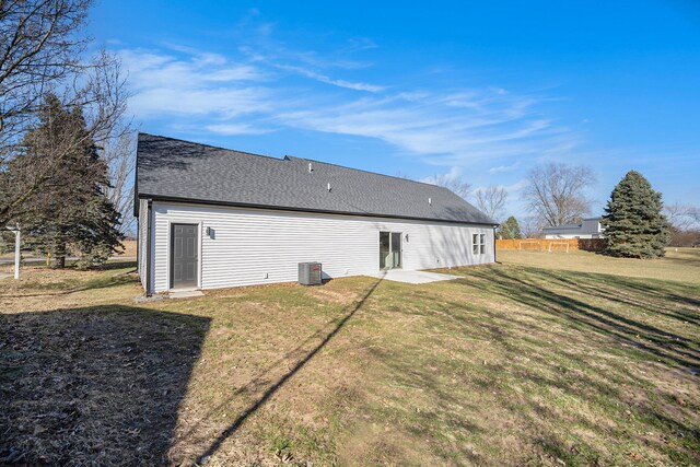 back of house with a patio area, a lawn, and roof with shingles