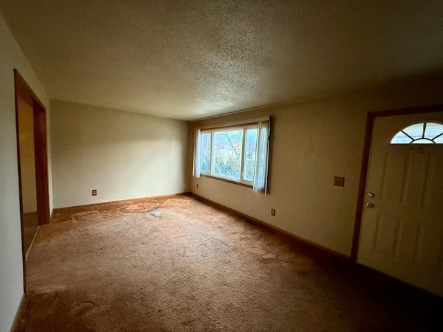 carpeted entrance foyer featuring a textured ceiling and baseboards