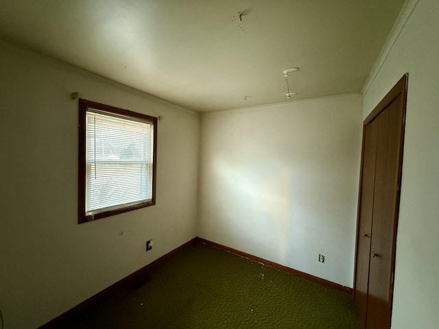 empty room featuring crown molding, carpet floors, and baseboards