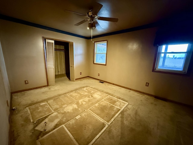 unfurnished bedroom with crown molding, a closet, a ceiling fan, and baseboards