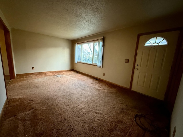 carpeted foyer featuring baseboards and a textured ceiling