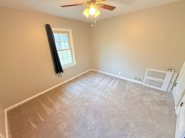 carpeted spare room with a ceiling fan, visible vents, and baseboards