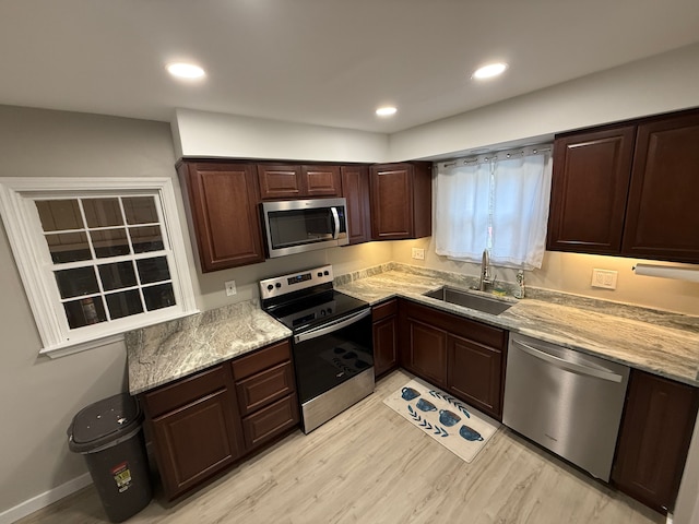 kitchen with stainless steel appliances, recessed lighting, light wood-style floors, a sink, and dark brown cabinets