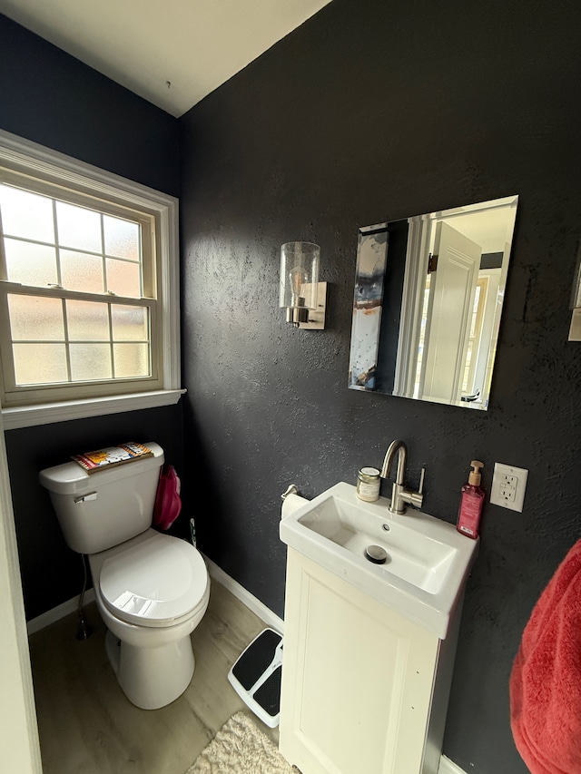 half bathroom featuring baseboards, a textured wall, toilet, and wood finished floors