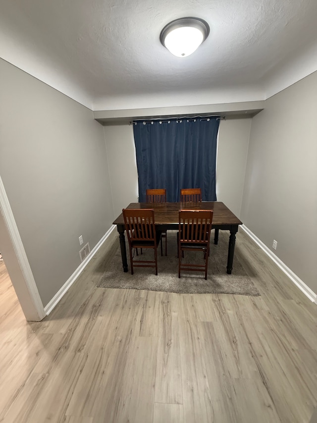 dining area featuring visible vents, a textured ceiling, baseboards, and wood finished floors