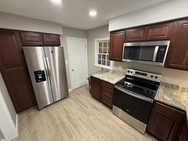 kitchen with stainless steel appliances, dark brown cabinets, and light wood-style flooring