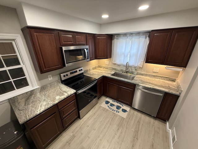 kitchen featuring light wood finished floors, stainless steel appliances, recessed lighting, a sink, and dark brown cabinets