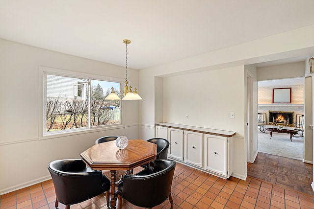 tiled dining area with a fireplace and baseboards