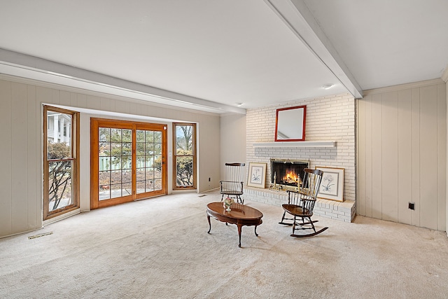 sitting room featuring a brick fireplace, visible vents, carpet flooring, and beamed ceiling