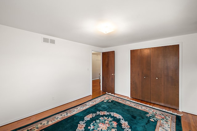 unfurnished bedroom with a closet, visible vents, and wood finished floors