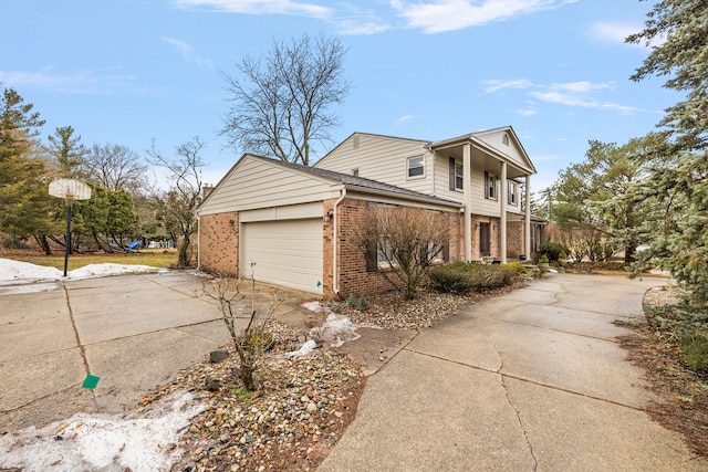 view of side of property featuring a garage, concrete driveway, and brick siding