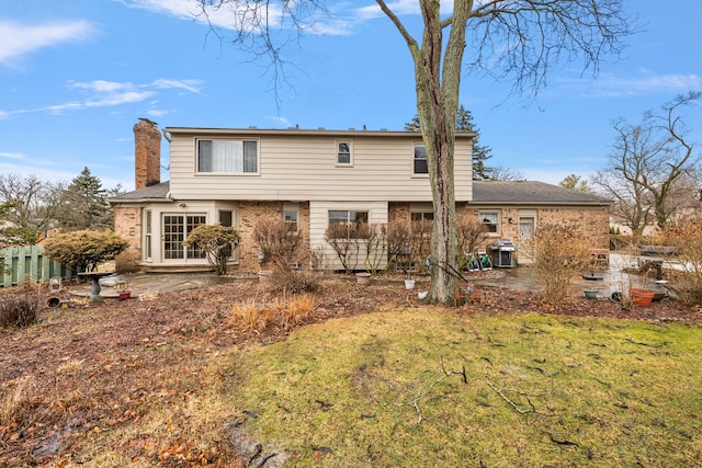 back of property with a patio, brick siding, fence, a yard, and a chimney